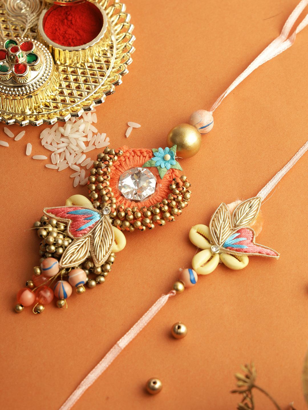 

Aapno Rajasthan Set of 2 Floral Beads Bhaiya Bhabhi Rakhi with Roli Chawal & Greeting Card, Orange