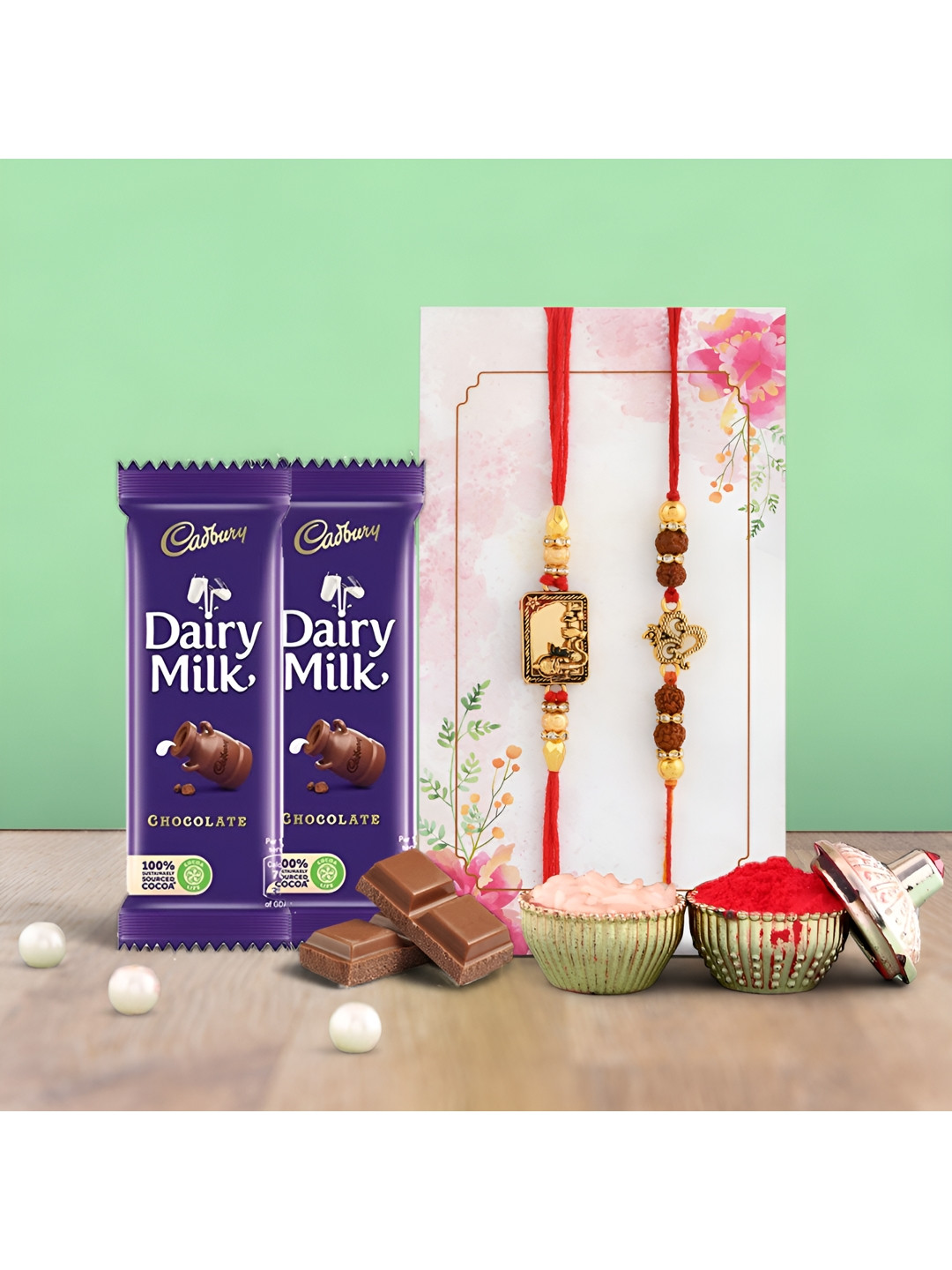

Ascension Set Of 2 Rakhi With Cedbury Dairy Milk Chocolates & Roli Tilak, Blue