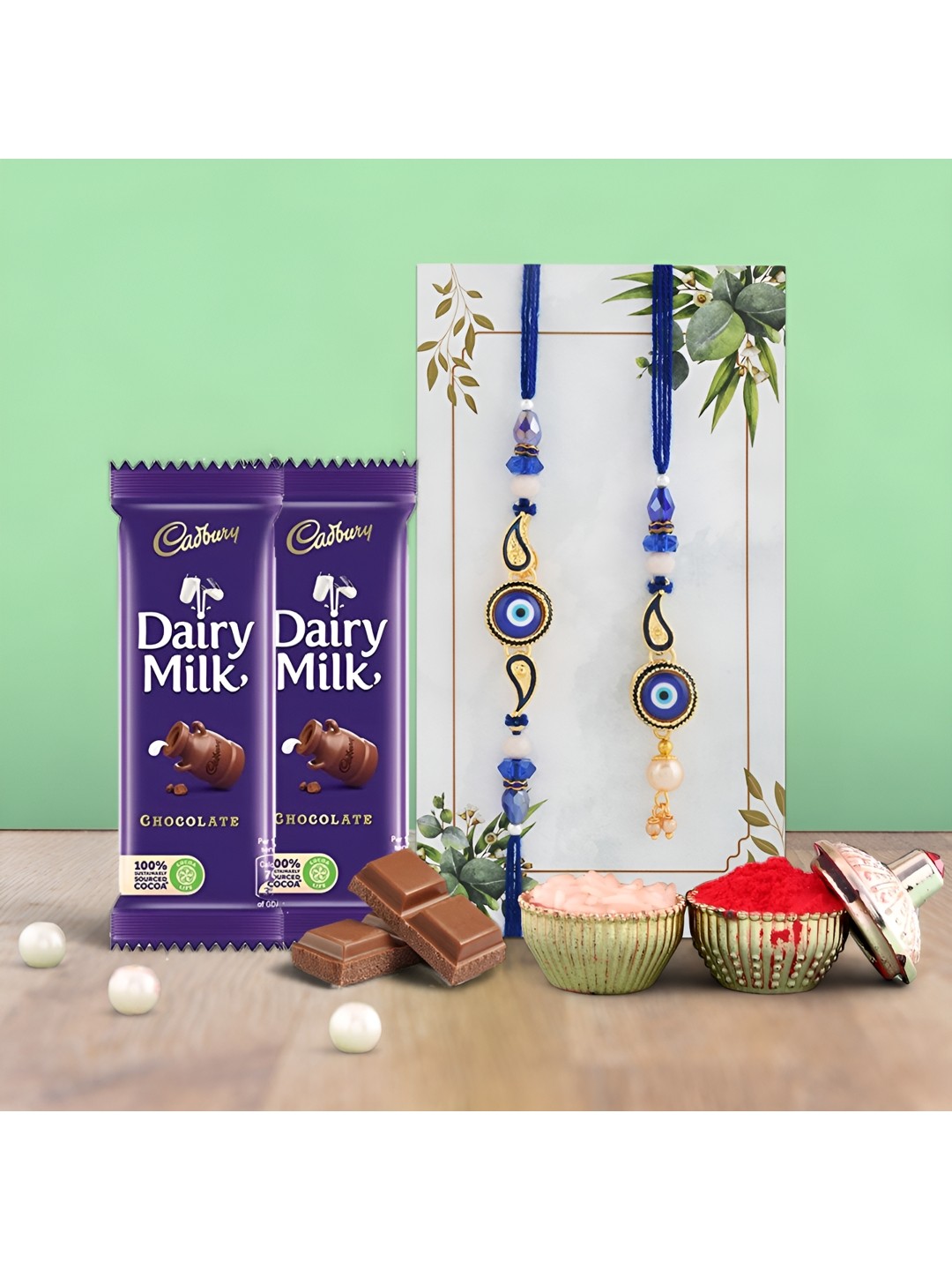 

Ascension Set of 2 Rakhi With Dairy Milk Chocolates & Greeting Card With Roli Chawal, Blue