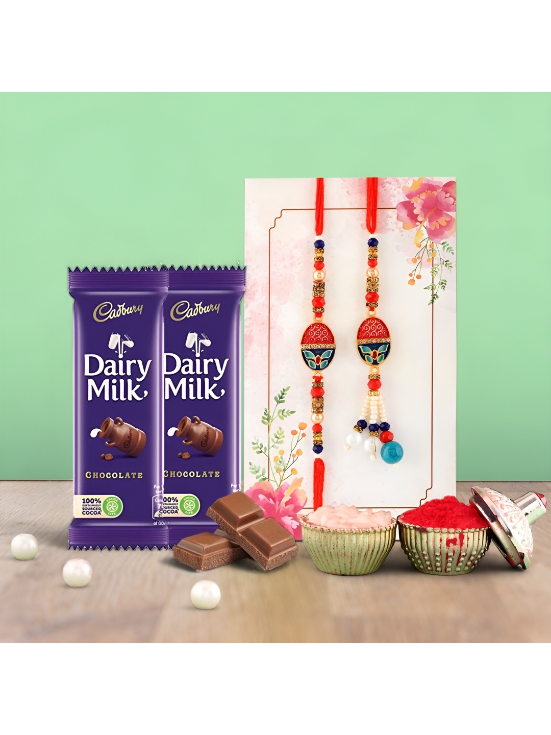 

Ascension Set Of 2 Bhaiya Bhabhi Rakhis With Cedbury Dairy Milk Chocolates & Rholi Chawal, Blue