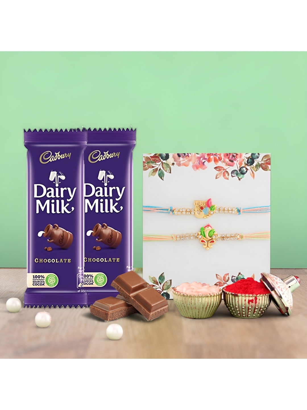 

Ascension Set Of 2 Rakhis With Cedbury Dairy Milk Chocolates With Rholi Chawal, Blue