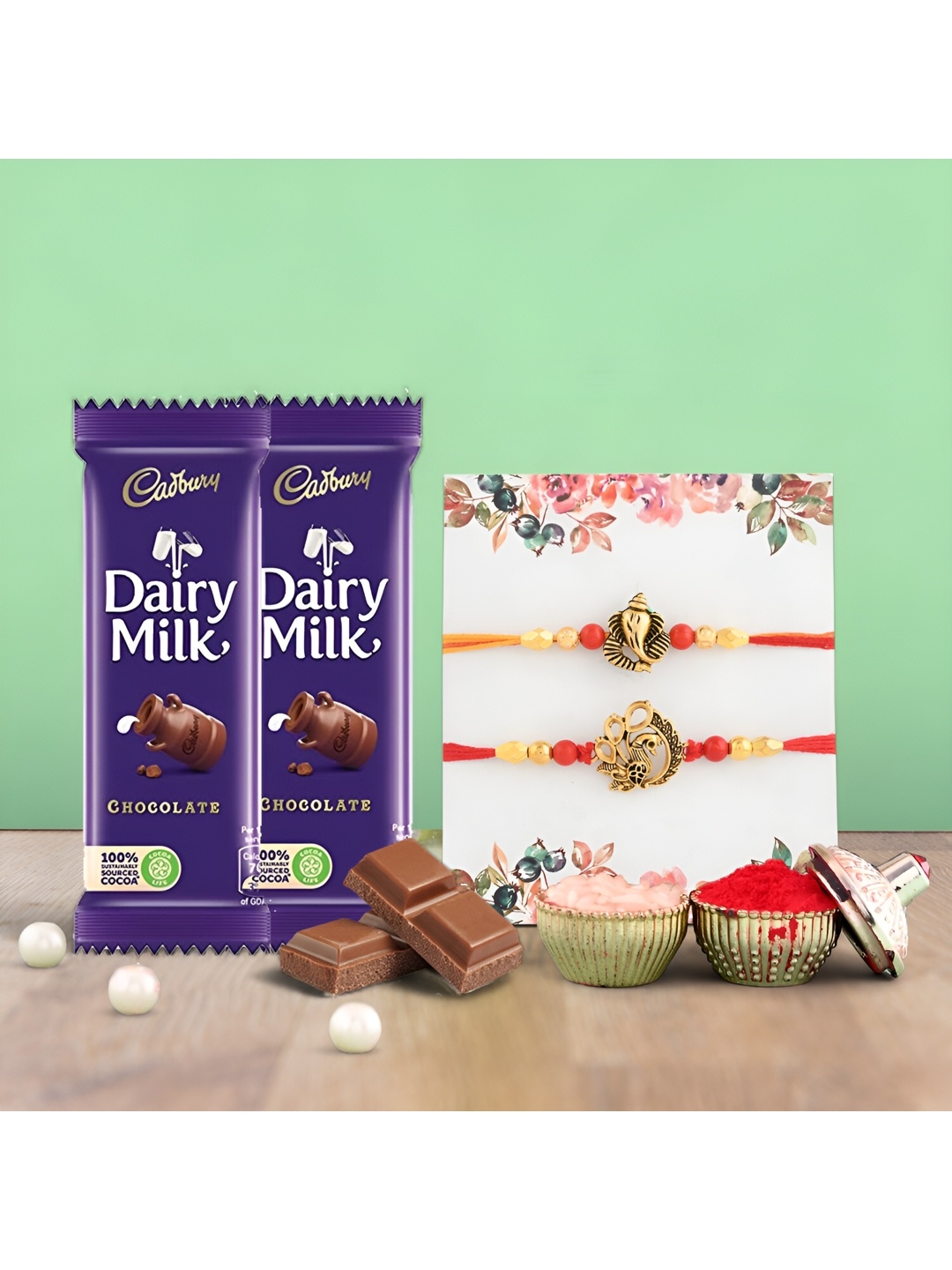 

Ascension Set of 2 Rakhi With Cedbury Dairy Milk Chocolates & Roli Tilak, Red