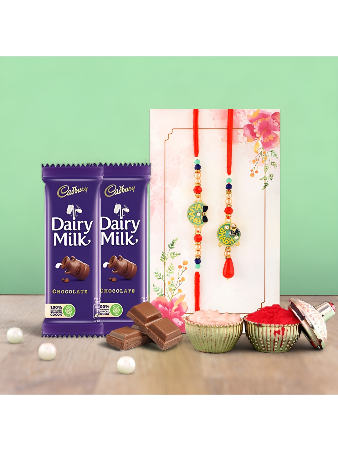 

Ascension Set of 2 Rakhi With Dairy Milk Chocolates & Greeting Card With Roli Chawal, Red
