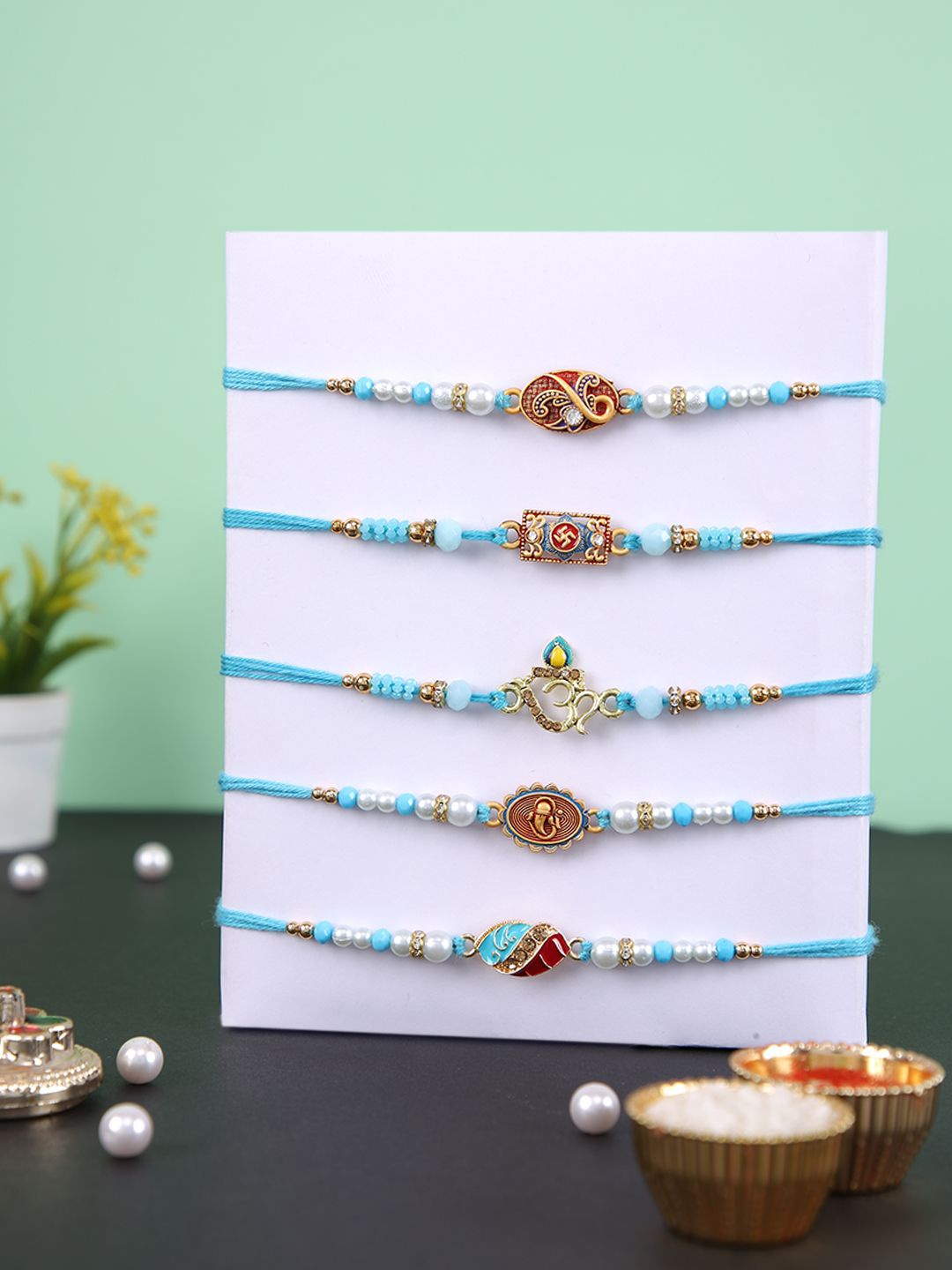 

Aapno Rajasthan Set Of 5 Stone Studded & Beaded Rakhis With Rholi Chawal & Greeting Card, Blue