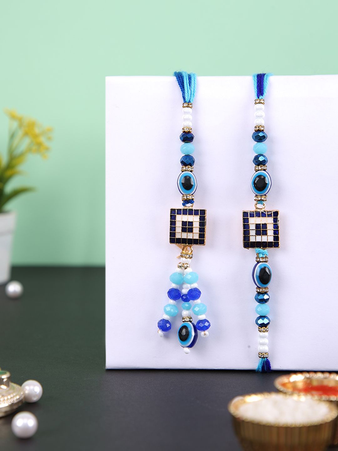 

Aapno Rajasthan Evil Eye Bhaiya Bhabhi Rakhis With Rholi Chawal & Greeting Card, Blue