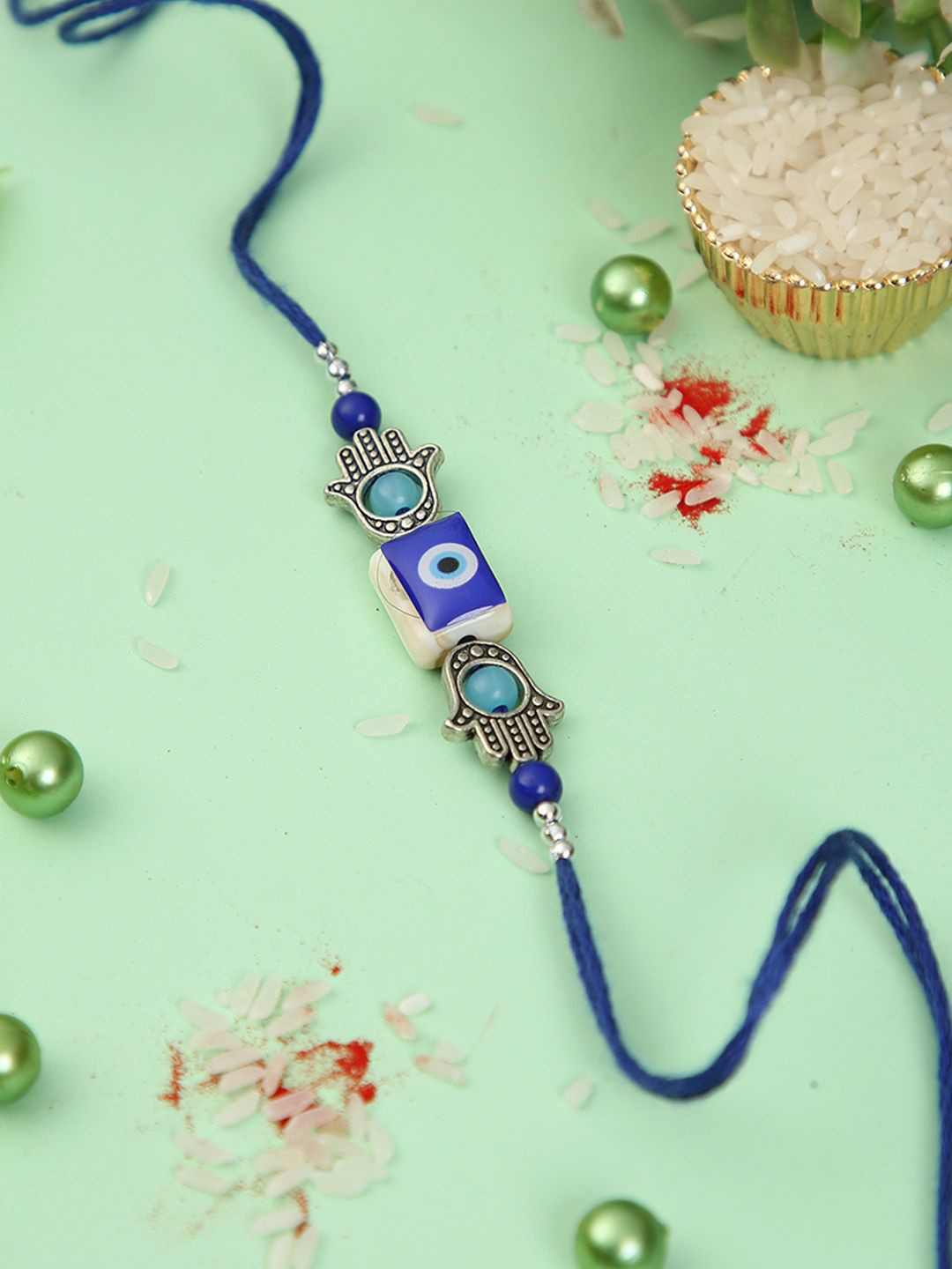 

Aapno Rajasthan Evil Eye Hamsa Hand Rakhi With Roli Chawal & Greeting Card, Blue