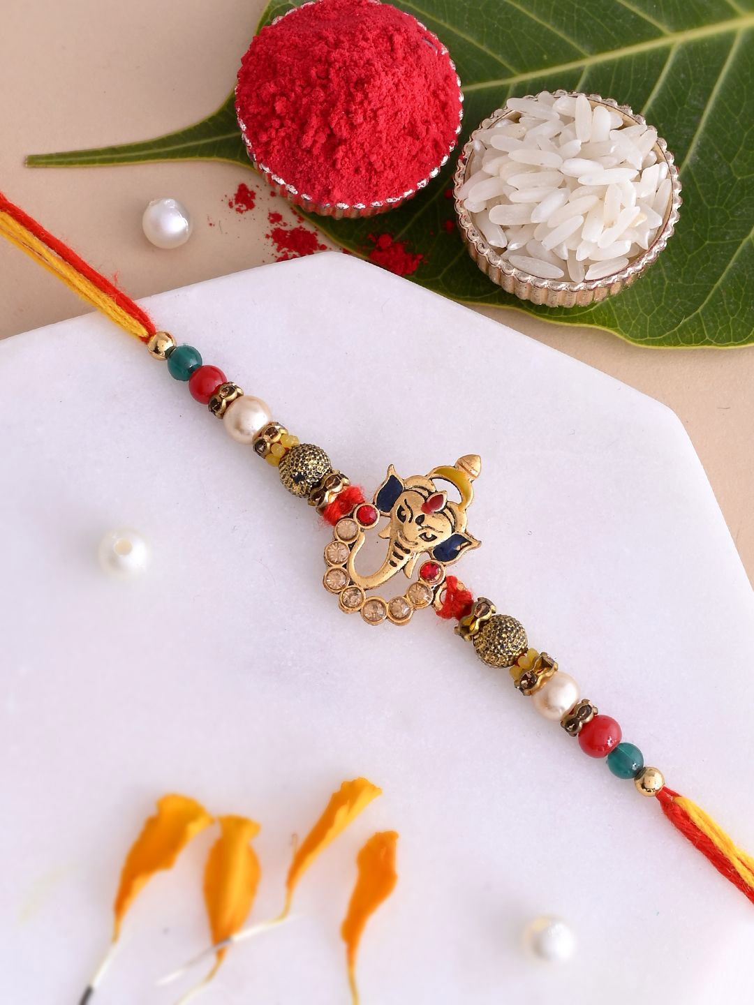 

Aapno Rajasthan Stone Studded & Ganesha Beaded Rakhi With Roli Chawal & Greeting Card, Gold
