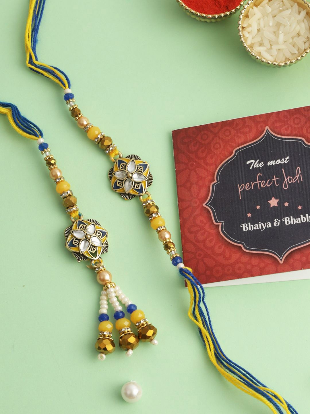 

Tied Ribbons Set of 2 Bhaiya Bhabhi Couple Rakhi, Card & Tikka Set, Gold