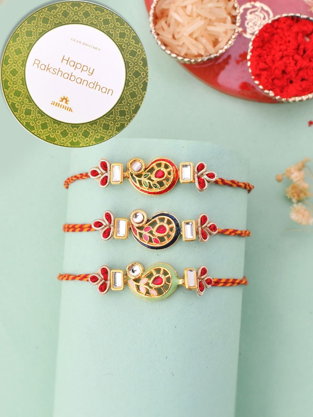 

Anouk Gold Toned Set of 3 Kundan Work Thread Rakhis With Roli Chawal & Greetings Card, Red