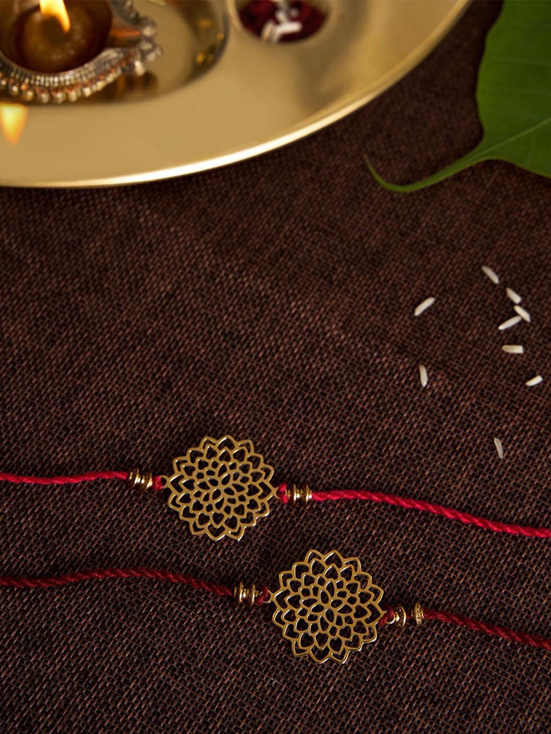 

DecorTwist Set Of 2 Om Charm Designed Thread Rakhis With Roli Chawal, Gold