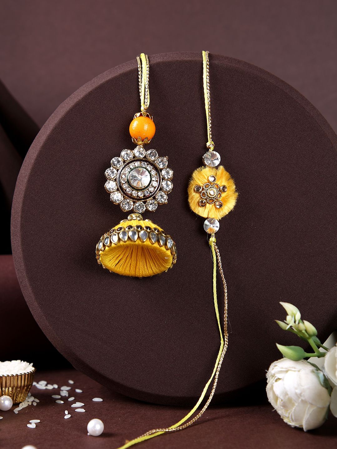 

Aapno Rajasthan Flower Lumba Bhaiya Bhabhi Rakhi With Roli Chawal & Greetings Card, Gold