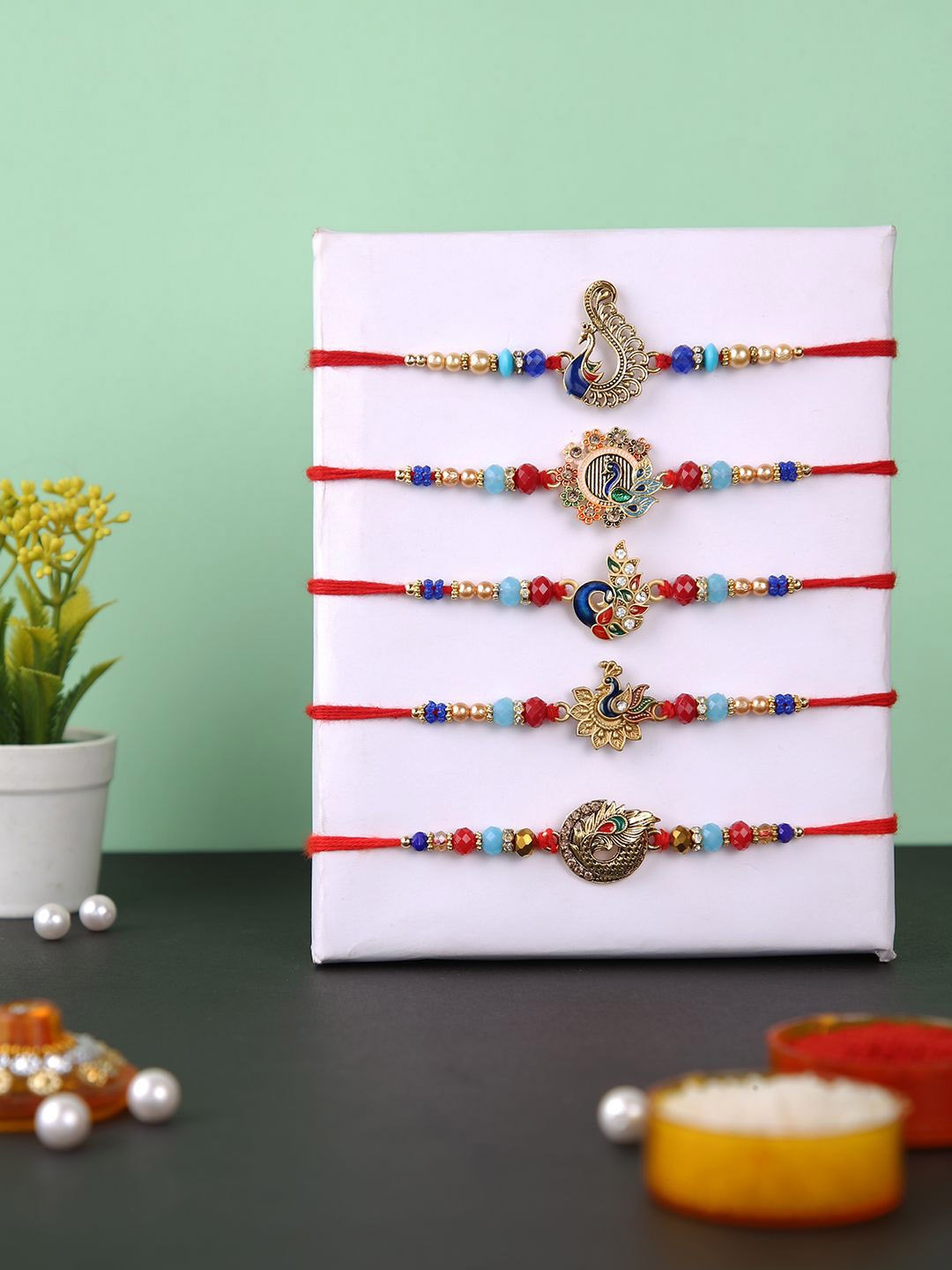 

Aapno Rajasthan Set of 5 Beaded Thread Rakhis with Roli Chawal & Greetings Card, Red