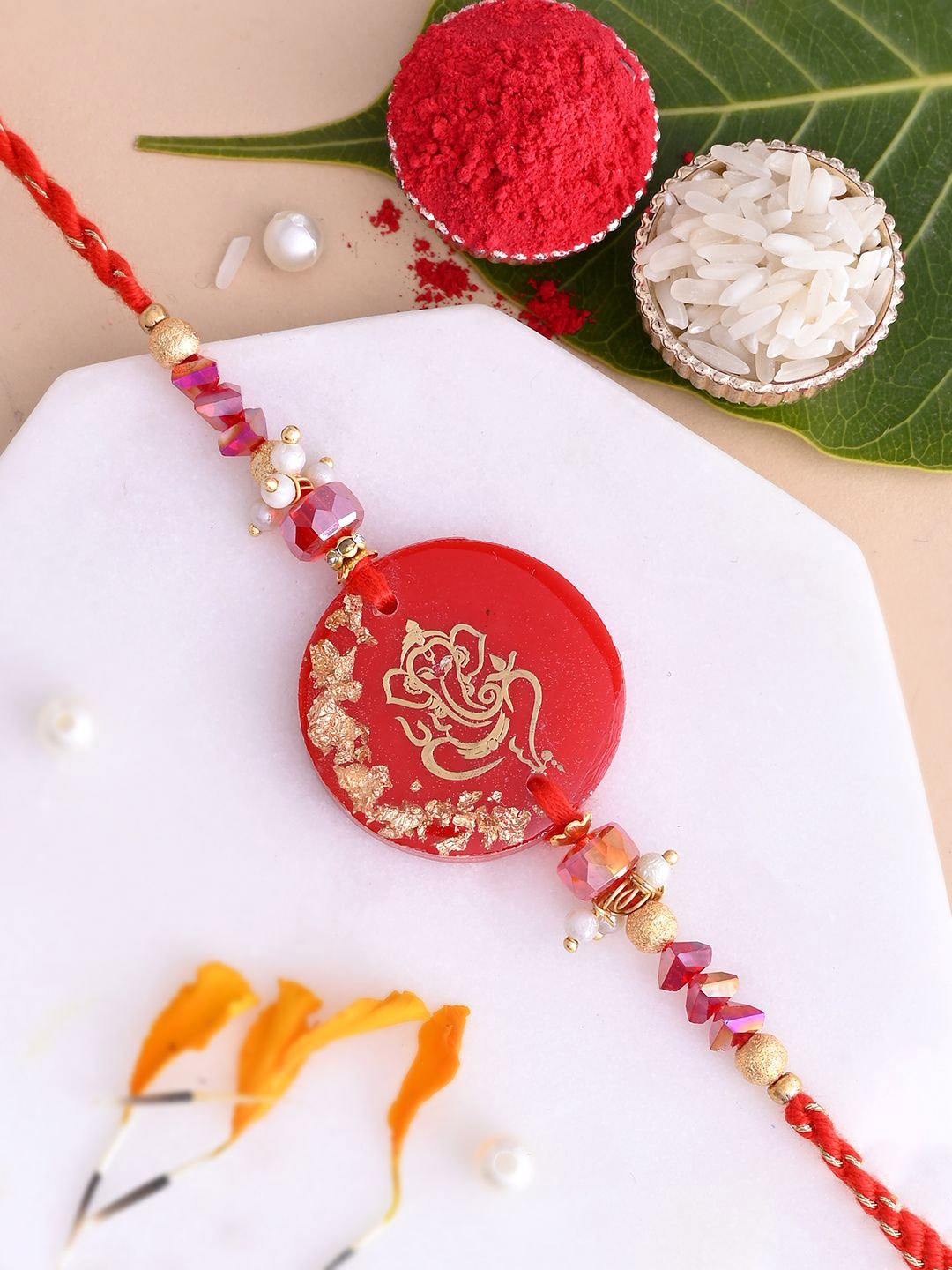 

Aapno Rajasthan Lord Ganesha Beaded Rakhi With Roli Chawal & Greetings Card, Red