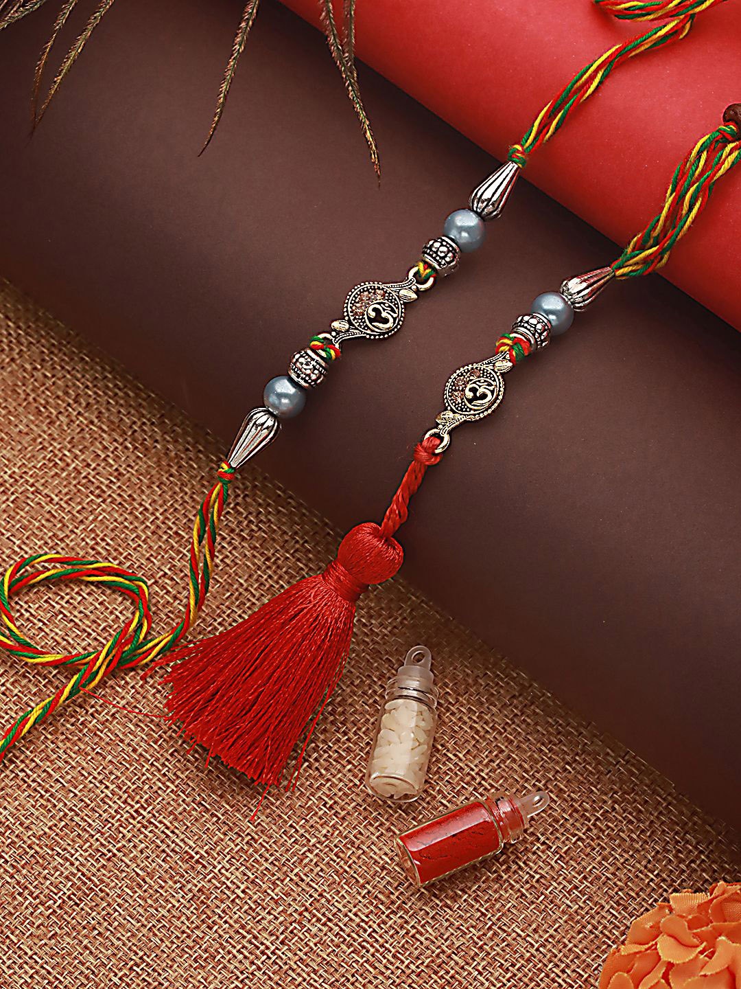 

Jazz and Sizzle Set of 2 Om & Pearl Beaded Tasselled Rakhi With Roli & Chawal, Red