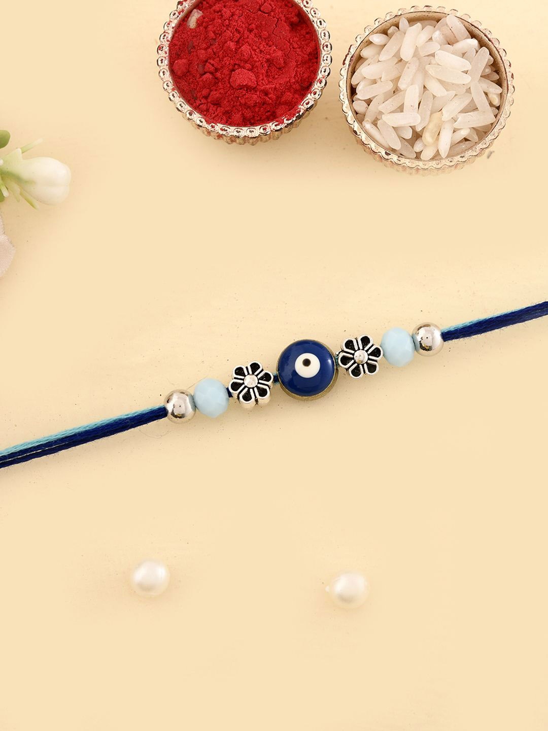 

Aapno Rajasthan Evil Eye Floral Beaded Thread Rakhi With Roli Chawal & Greeting Card, Blue
