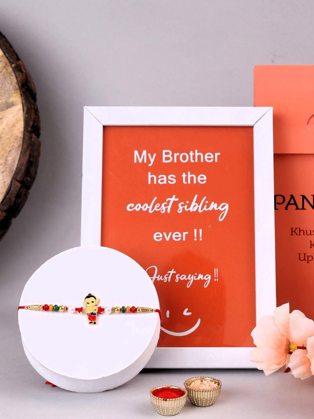 

PANASH Gold Plated Ganesh Shaped Rakhi With Gift Set Of Photo Frame & Roli Chawal