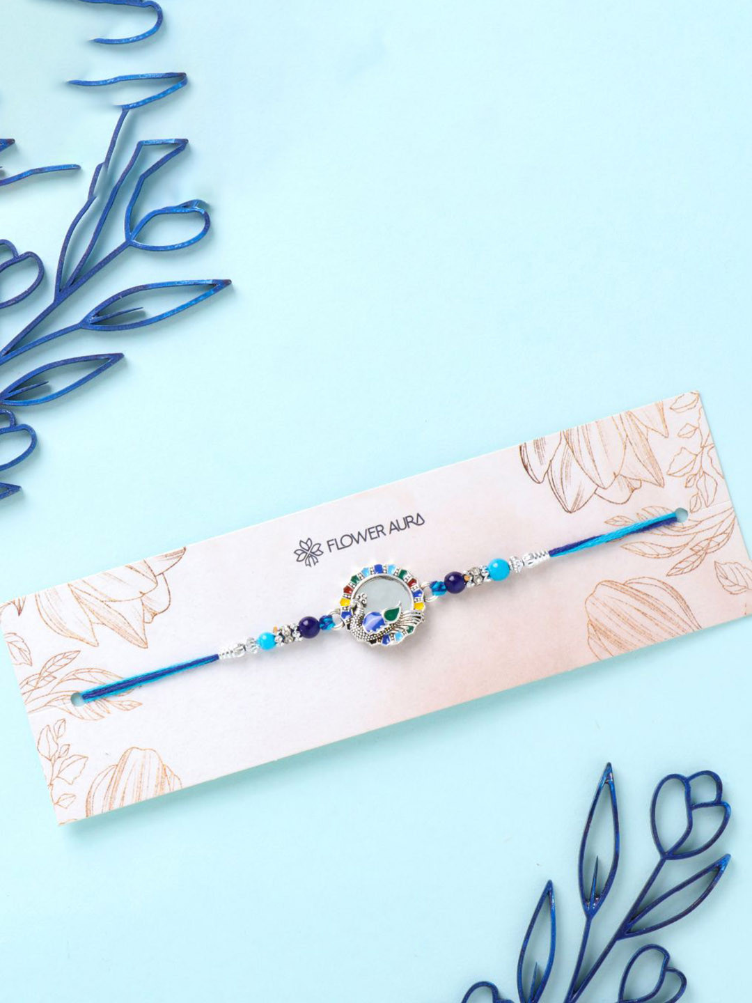 

Floweraura Stone Studded & Beaded Peacock Charm Thread Rakhi With Roli Chawal, Blue