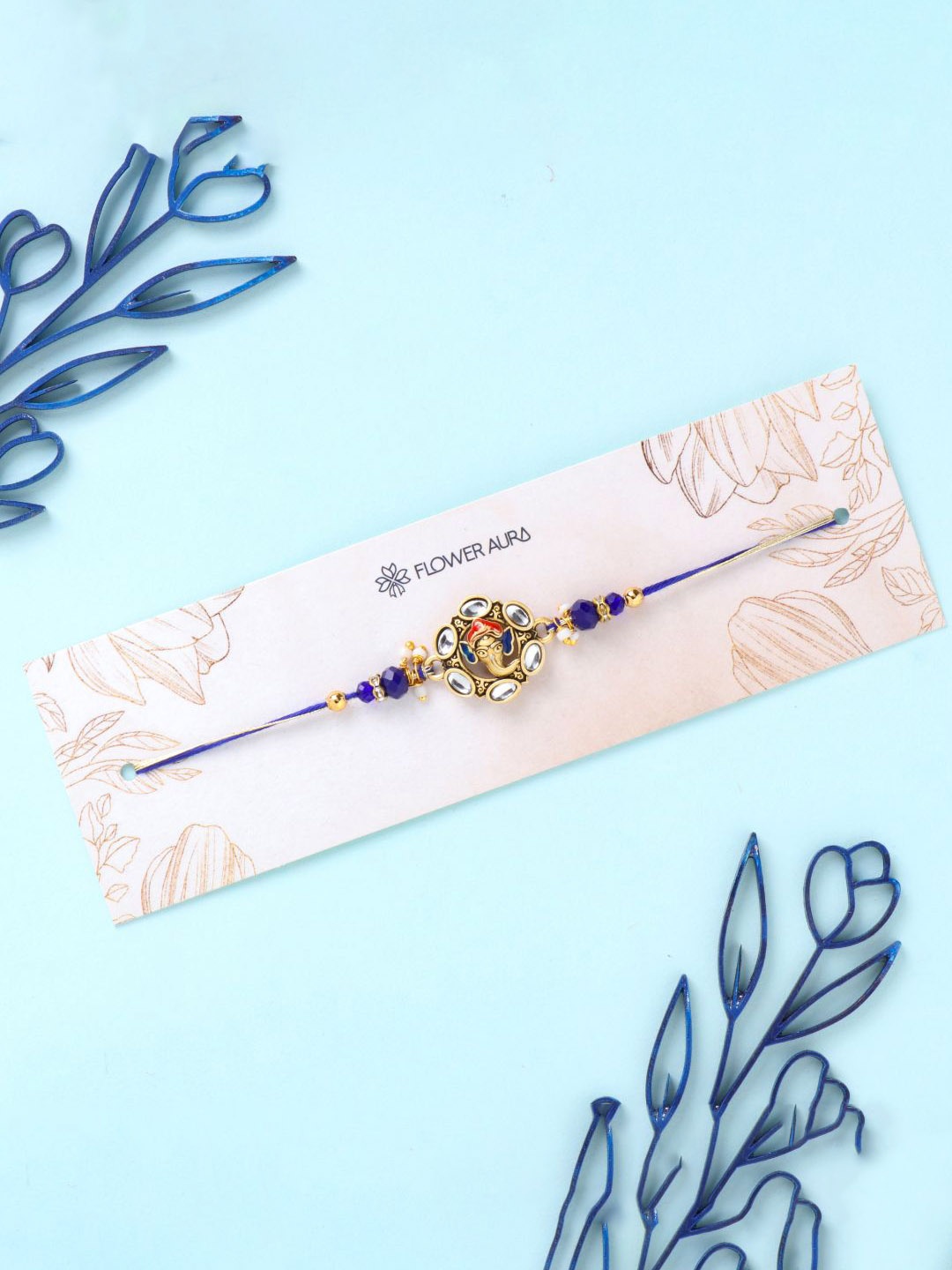 

Floweraura Divine Ganesha Stone Studded Thread Rakhi With Roli Chawal, Blue