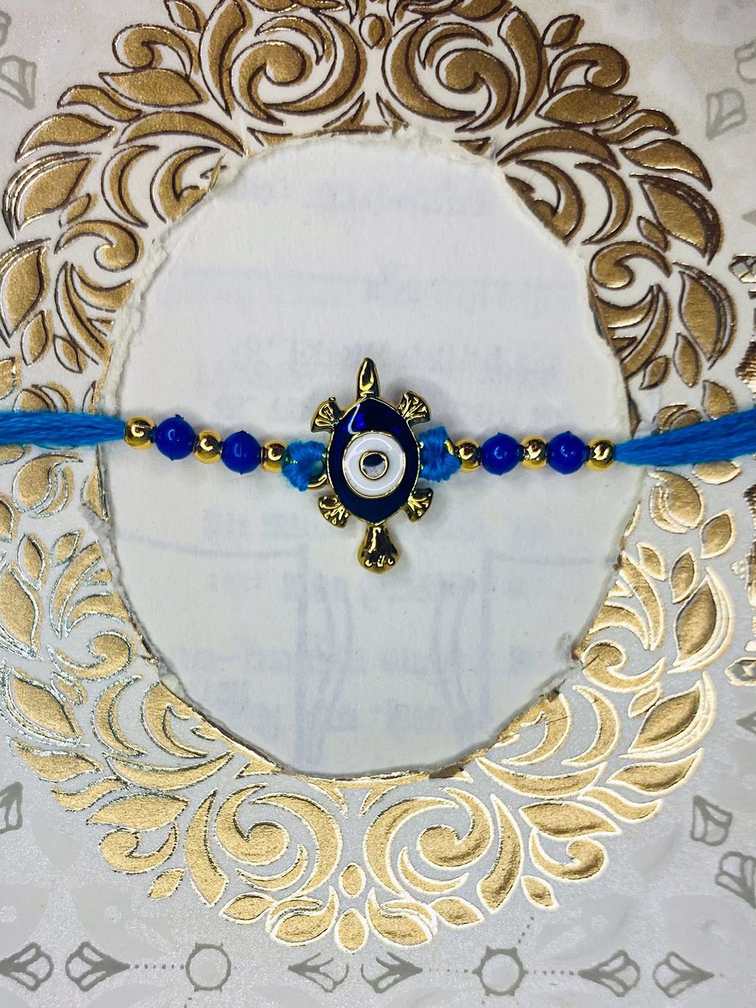 

Mahi Evil Eye & Tortoise-Shaped Stone Studded & Beaded Thread Rakhi, Blue
