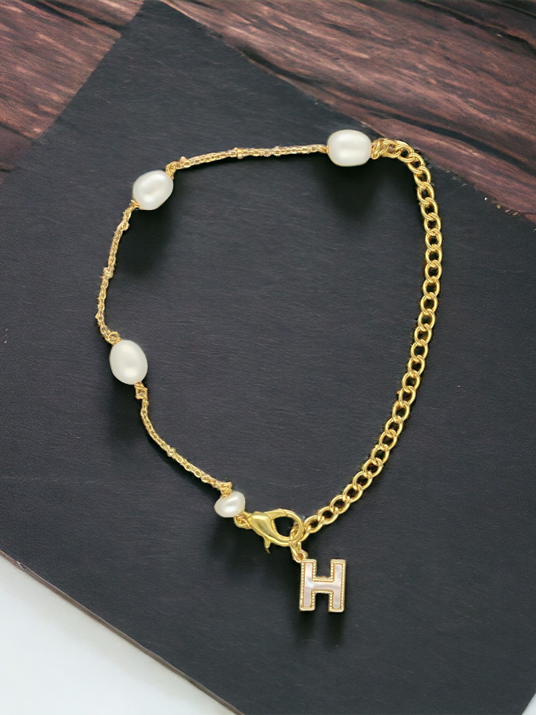 

Sri Jagdamba Pearls Dealer Gold-Plated Mother of Pearl Studded H Alphabet Charm Bracelet