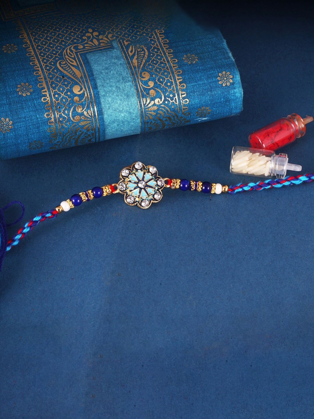 

Vighnaharta Gold and Rhodium Plated Flower Thread Rakhi with Roli Chawal, Blue
