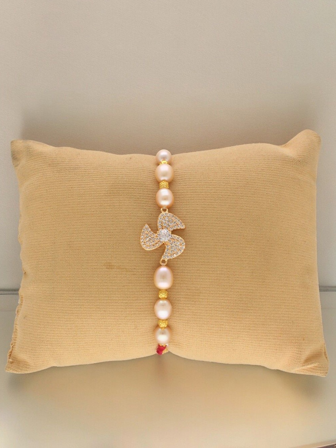 

Sri Jagdamba Pearls Dealer Stone Studded Fresh Water Pearl Beaded Thread Rakhi, White