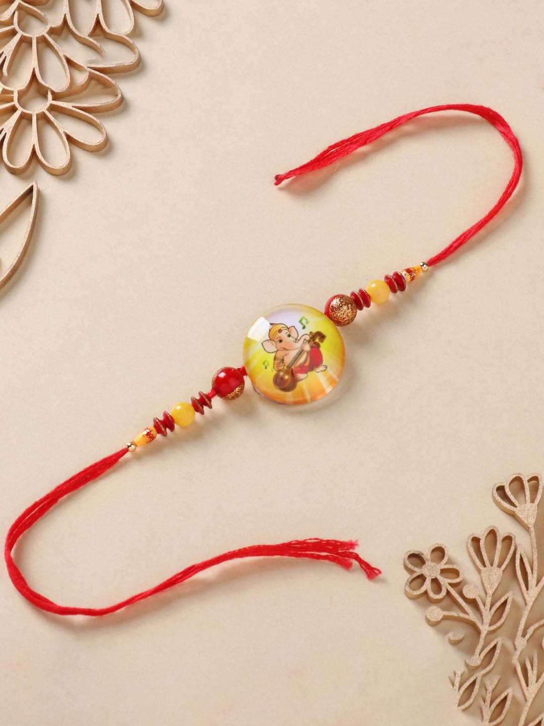 

Floweraura Kids Beaded Gleaming Ganpati Thread Rakhi with Roli Chawal, Yellow