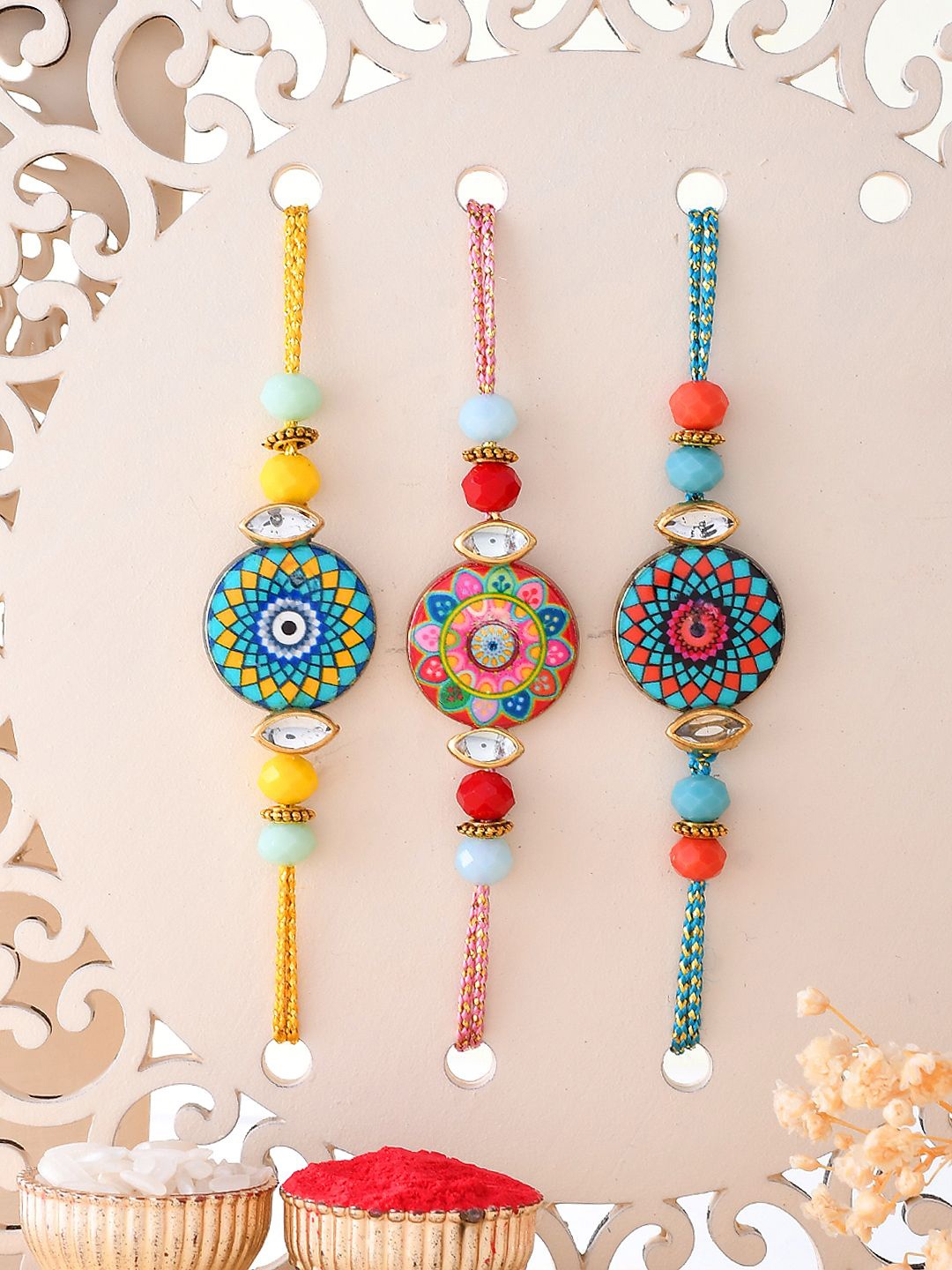

Sangria Yellow & Red Set of 3 Mandala Art Work Rakhis With Roli Chawal & Greetings Card