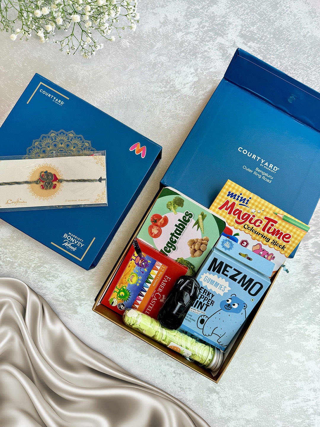 

Courtyard by Marriott - BLR ORR Kids Rakhi With 7Pcs Assorted Gift Hamper, Blue