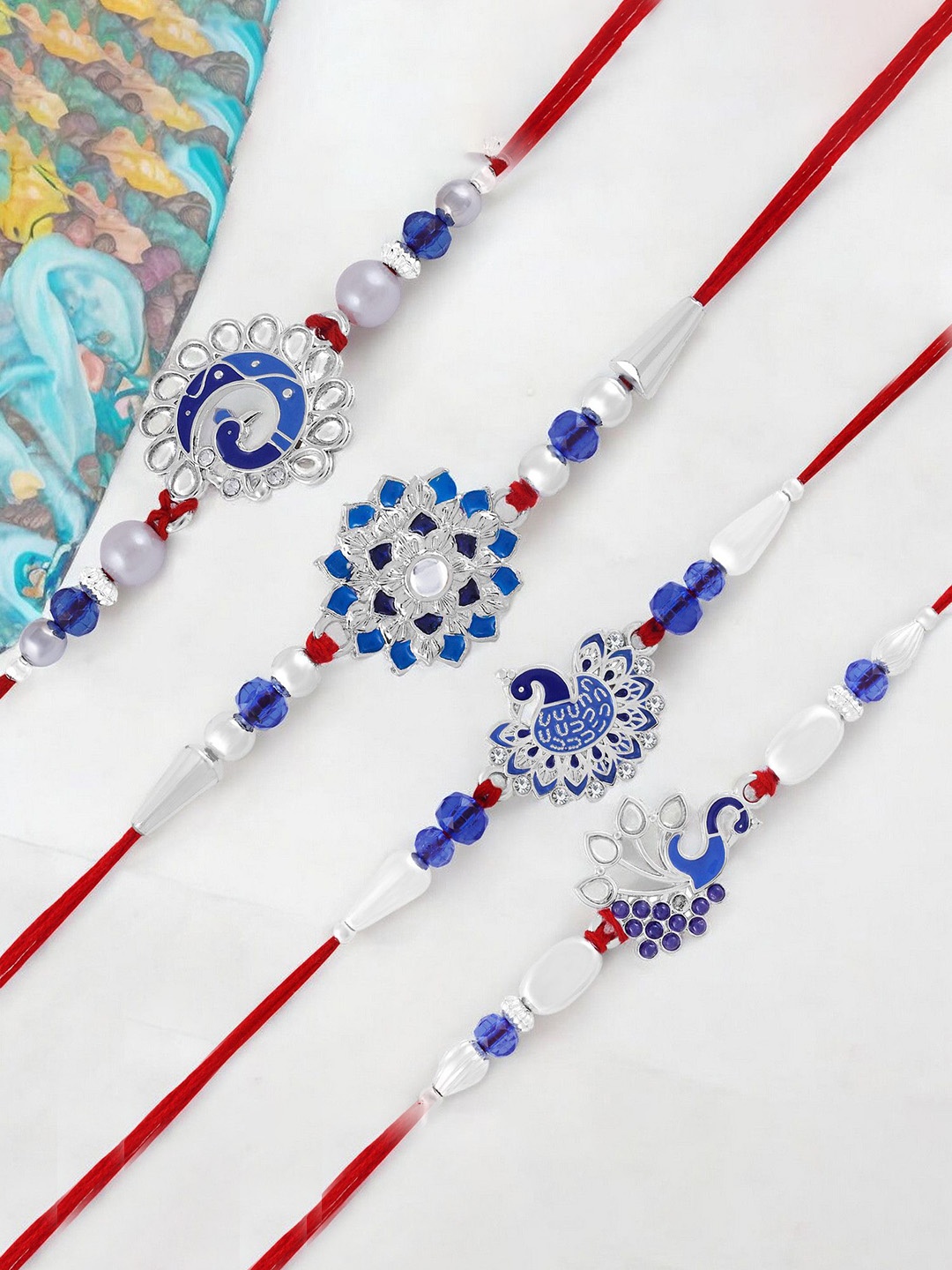 

Okos Set of 4 Rhodium Plated Dazzling Peacock and Floral Style Thread Rakhis, Silver