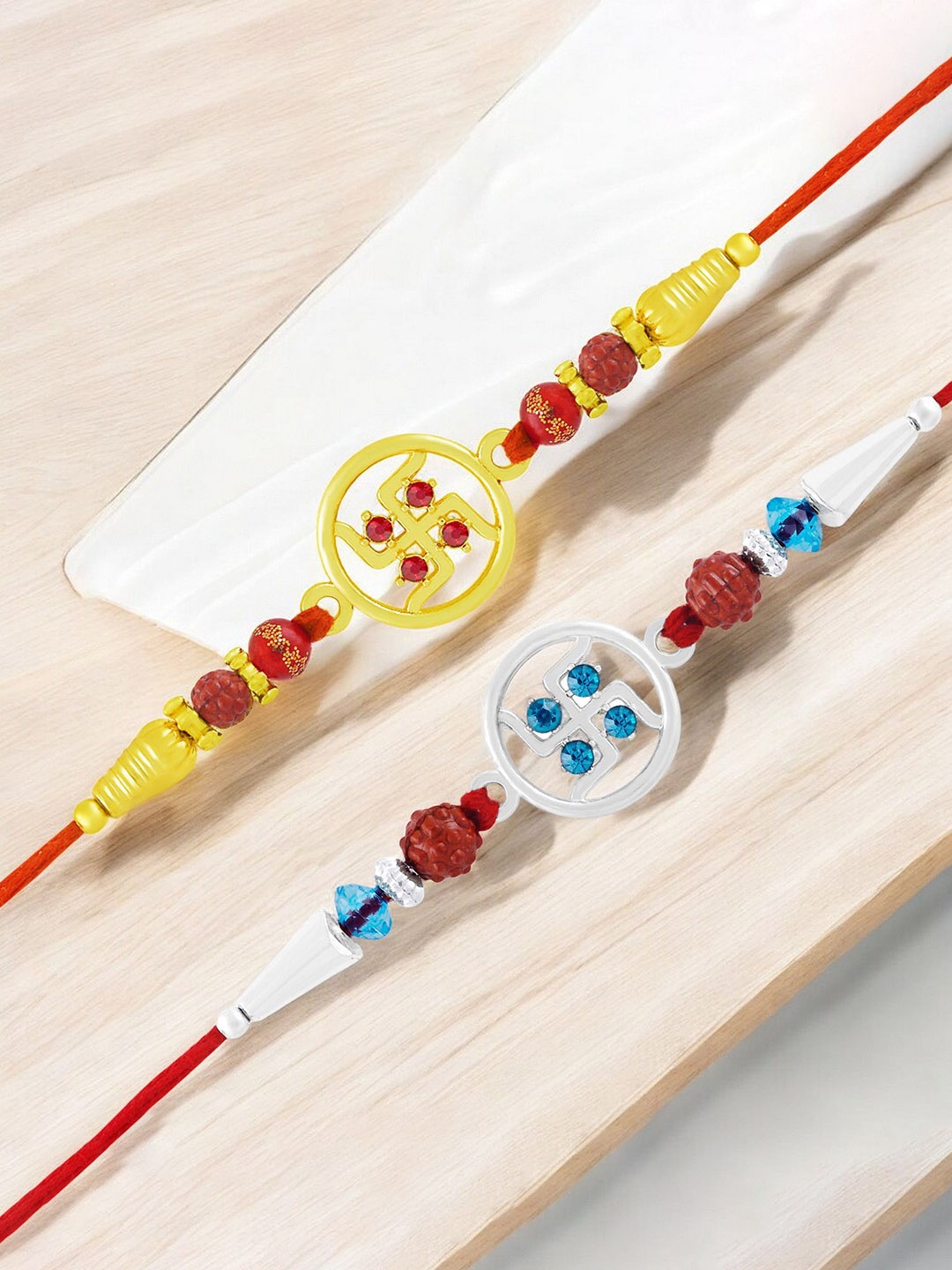 

Okos Set of 2 Gold and Rhodium Plated Auspicious Swastik Thread Rakhis, Red