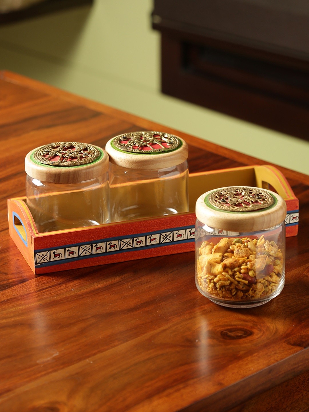 

ExclusiveLane 'Three's A Tribe' Dhokra Snacks Jar Set In Glass With Warli Hand-Painted Wooden Tray, Brown