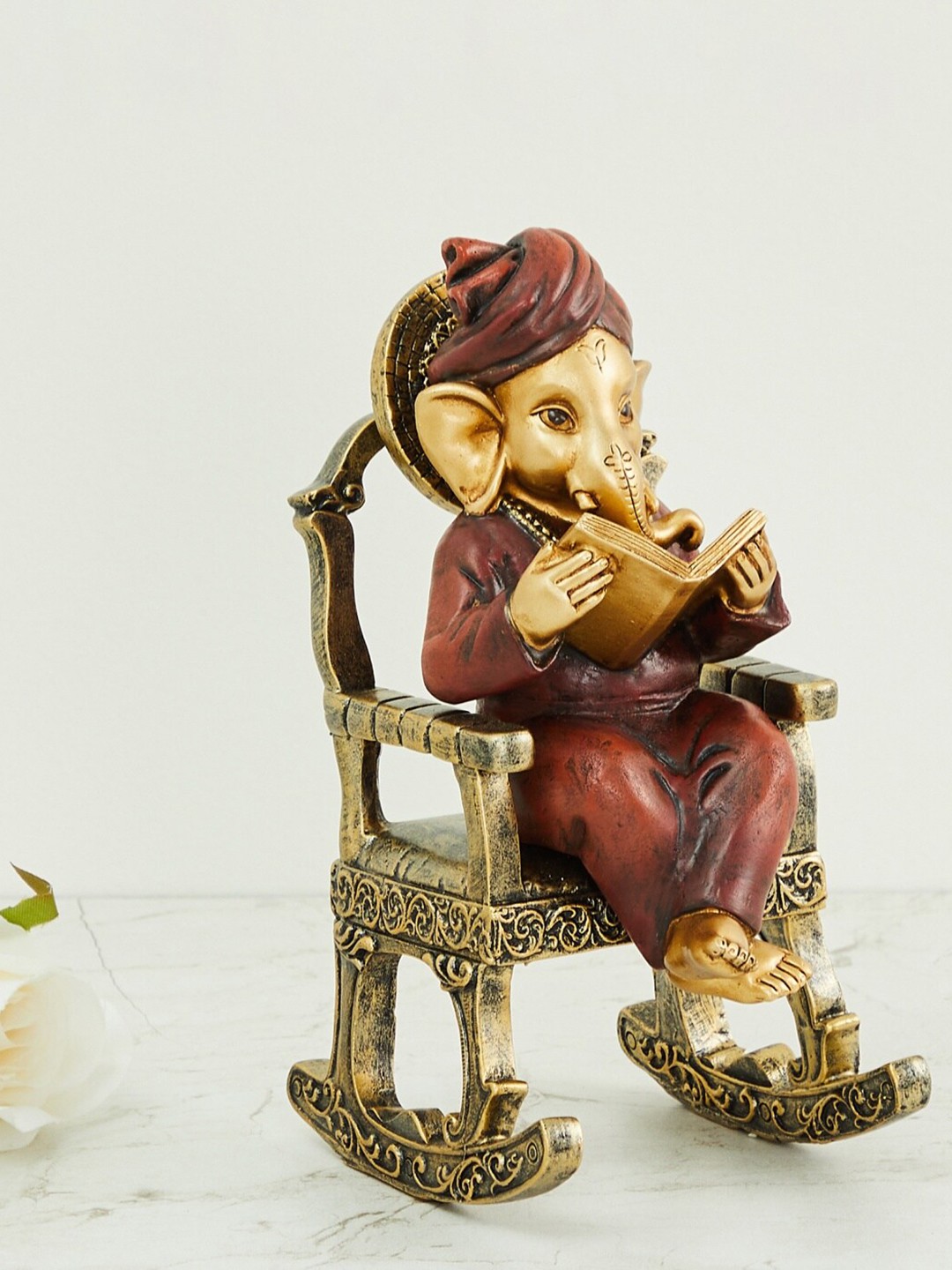 

Home Centre Maroon & Gold-Toned Alpana Ganesha Sitting on Chair Figurine Showpiece