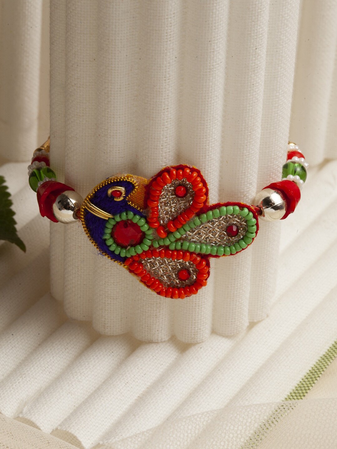

PANASH Red & Green Beaded Peacock Shaped Mauli Rakhi With Roli Chawal